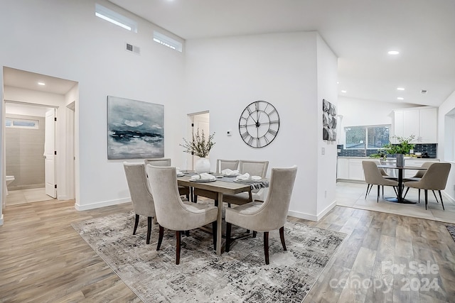 dining room with a towering ceiling and light hardwood / wood-style floors