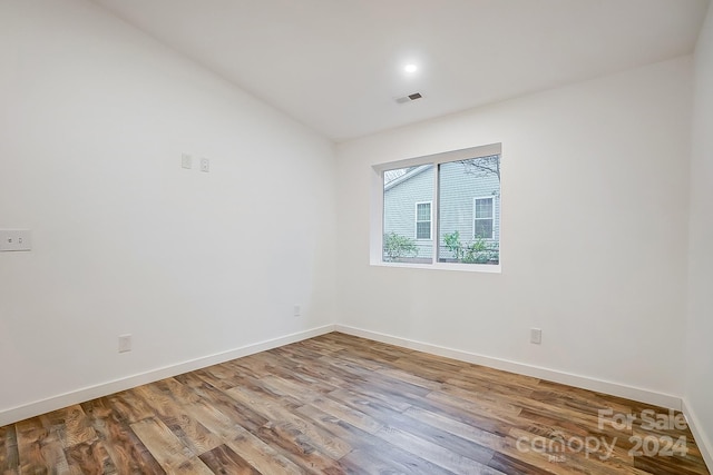 unfurnished room with hardwood / wood-style flooring and vaulted ceiling