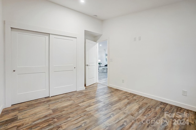 unfurnished bedroom with light hardwood / wood-style floors and a closet