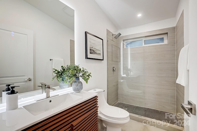 bathroom with tiled shower, vanity, and toilet