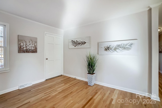 spare room featuring crown molding, hardwood / wood-style floors, and plenty of natural light