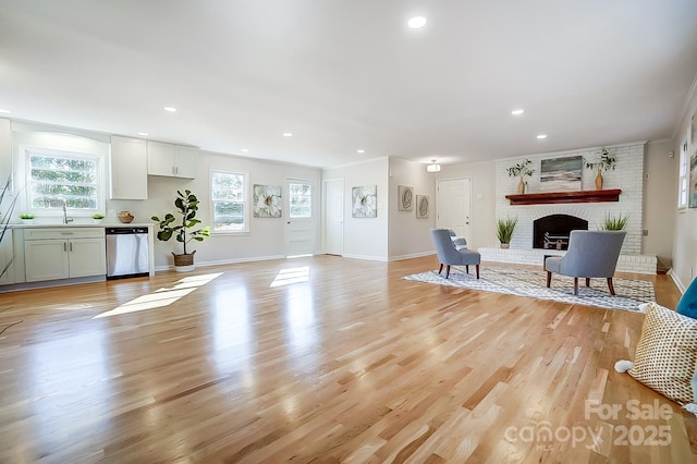 living room with a fireplace, light hardwood / wood-style flooring, and sink