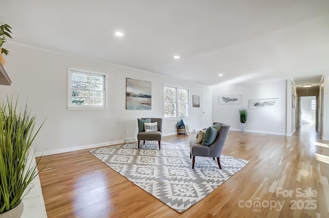 sitting room with light wood-type flooring and crown molding