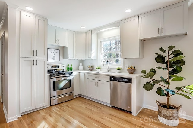 kitchen with sink, white cabinetry, stainless steel appliances, and light wood-type flooring