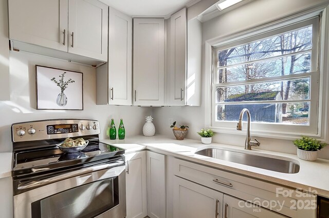 kitchen with white cabinetry, stainless steel range with electric stovetop, and sink