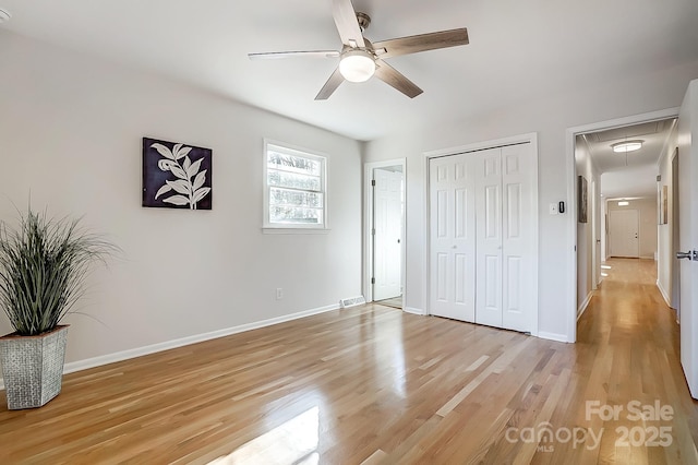 unfurnished bedroom featuring ceiling fan, light wood-type flooring, and a closet