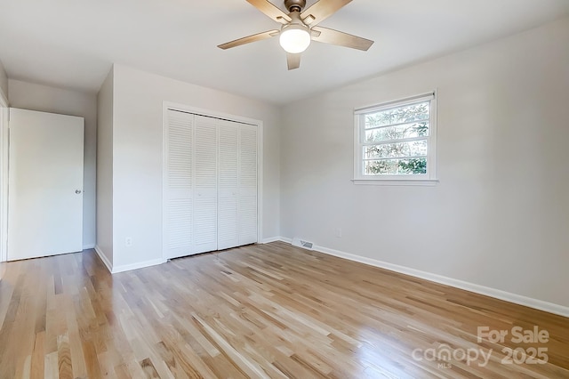 unfurnished bedroom with ceiling fan, light wood-type flooring, and a closet