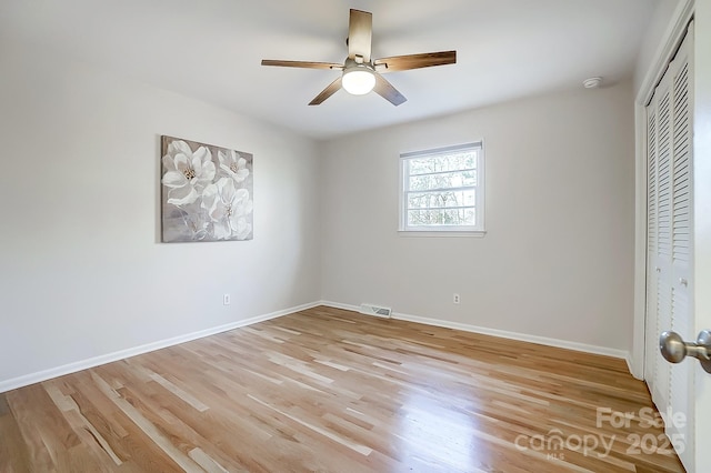 unfurnished bedroom featuring ceiling fan, light hardwood / wood-style floors, and a closet