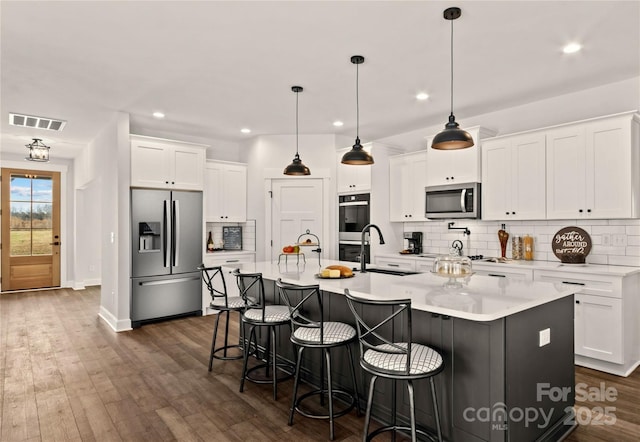 kitchen featuring white cabinets, appliances with stainless steel finishes, sink, and an island with sink