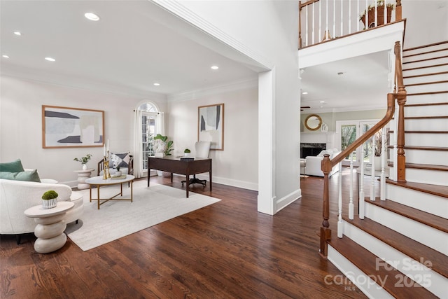 foyer featuring baseboards, stairway, dark wood-type flooring, crown molding, and a fireplace