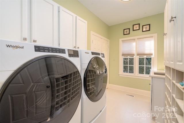 washroom with baseboards, cabinet space, visible vents, and washing machine and clothes dryer