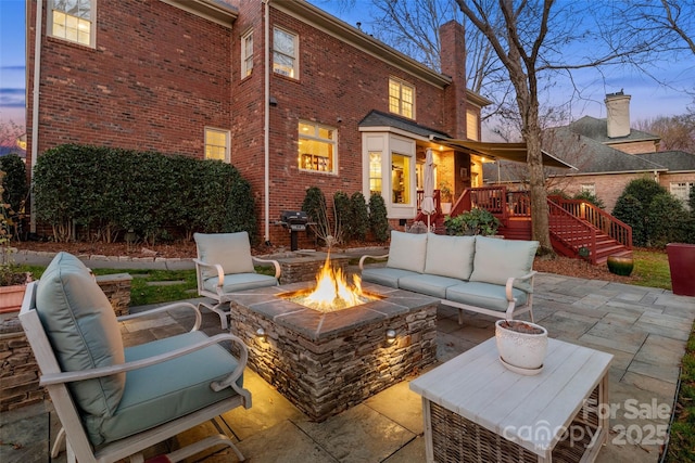 patio terrace at dusk featuring an outdoor living space with a fire pit and a wooden deck