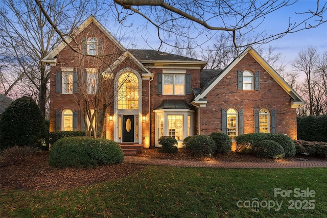 view of front of house featuring brick siding and a front lawn