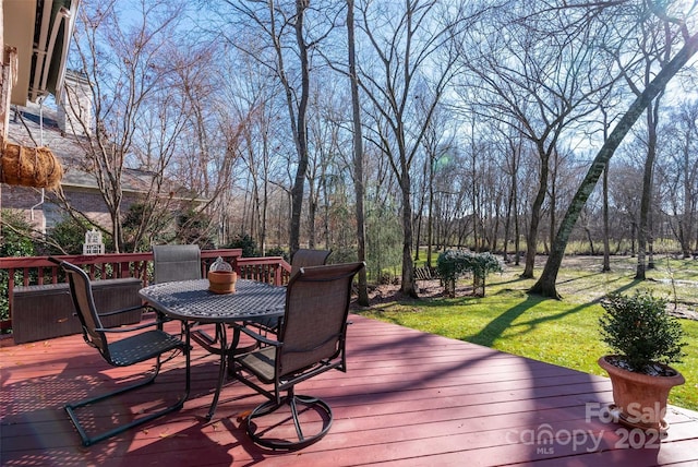 wooden terrace with outdoor dining area and a yard