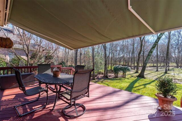 deck with outdoor dining area and a yard