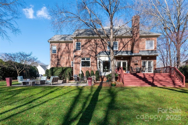 rear view of property featuring a fire pit, a patio area, brick siding, and a wooden deck