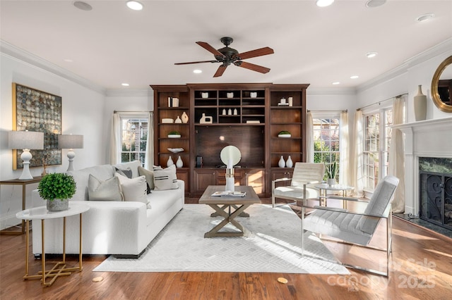 living area featuring light wood-type flooring, recessed lighting, a fireplace, and crown molding