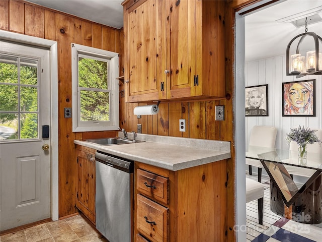 kitchen featuring hanging light fixtures, dishwasher, sink, and wooden walls