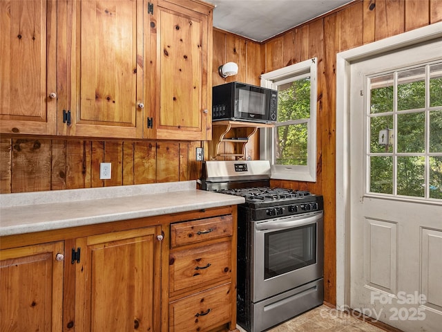 kitchen featuring gas range and wood walls