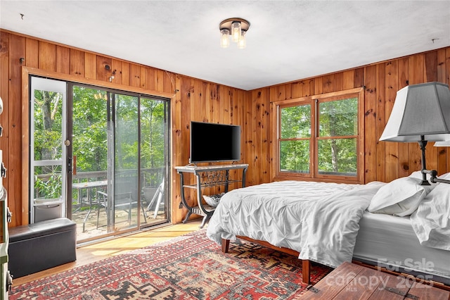 bedroom featuring multiple windows, access to exterior, and wood walls