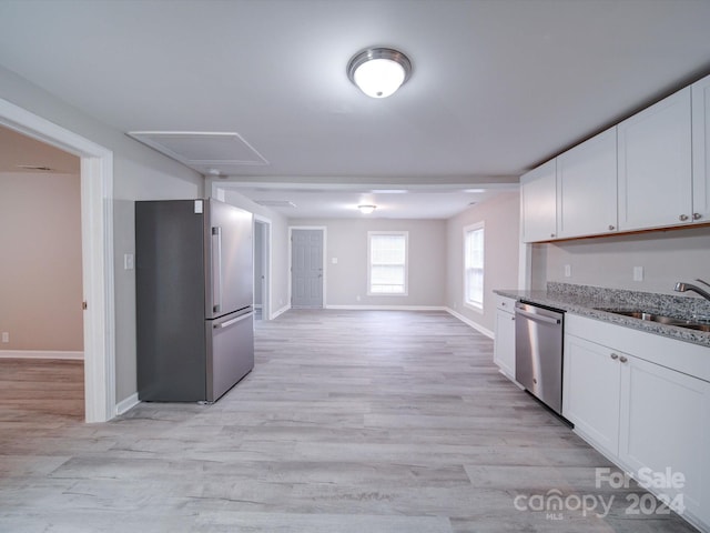 kitchen with light stone counters, stainless steel appliances, sink, white cabinets, and light hardwood / wood-style floors