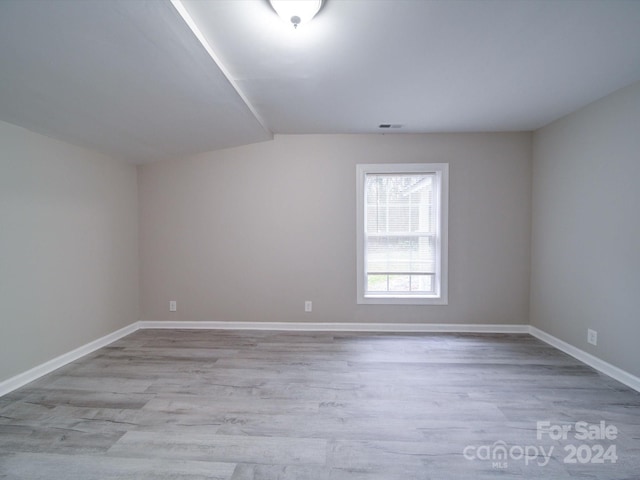 additional living space with light wood-type flooring and vaulted ceiling