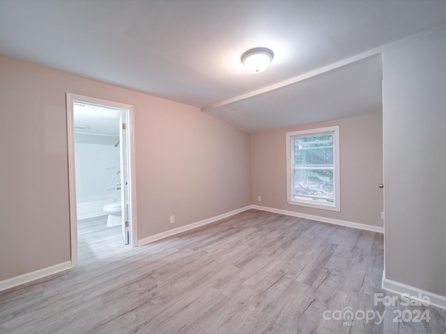 empty room featuring light wood-type flooring and vaulted ceiling