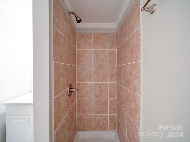 bathroom with vanity, crown molding, and tiled shower