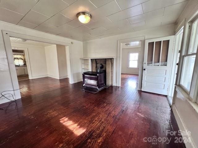 unfurnished living room with a wood stove and dark hardwood / wood-style flooring