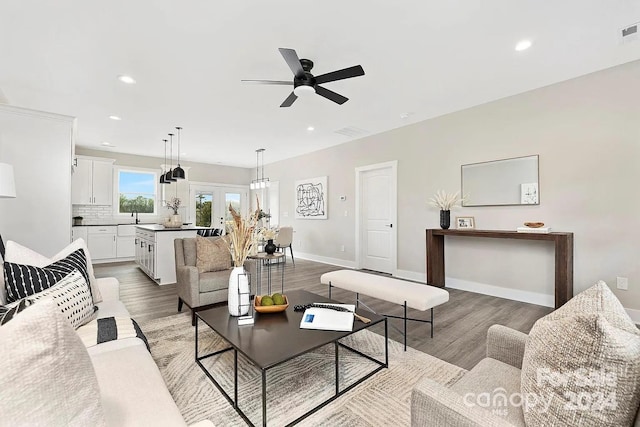 living room with ceiling fan, sink, and light hardwood / wood-style floors