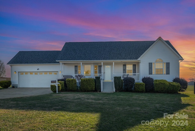 single story home with covered porch, a garage, and a lawn