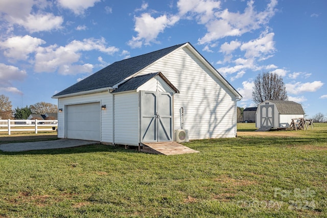 view of outbuilding with ac unit, a garage, and a yard