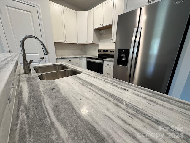 kitchen featuring light stone countertops, sink, stainless steel appliances, decorative backsplash, and white cabinets