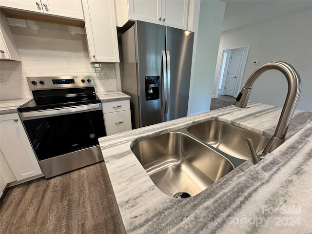 kitchen with white cabinetry, stainless steel appliances, light stone counters, dark hardwood / wood-style flooring, and decorative backsplash