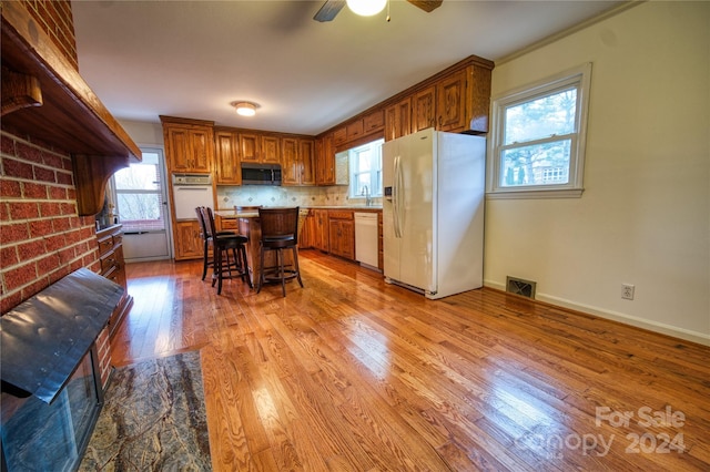 kitchen with white appliances, a center island, a wealth of natural light, and a breakfast bar