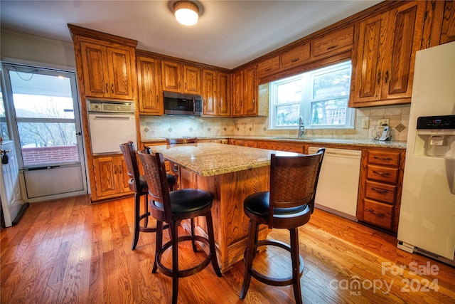 kitchen featuring white appliances, a center island, light hardwood / wood-style flooring, and plenty of natural light