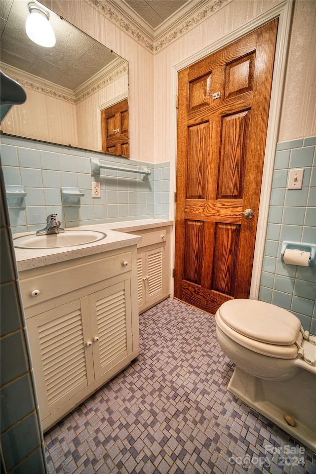 bathroom with crown molding, a textured ceiling, toilet, vanity, and tile walls