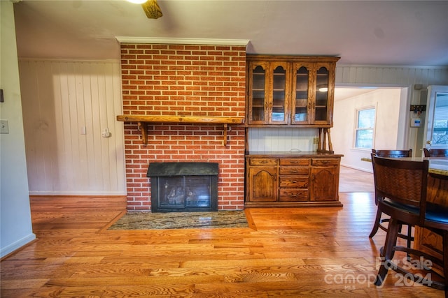 living room featuring crown molding, a fireplace, and light wood-type flooring