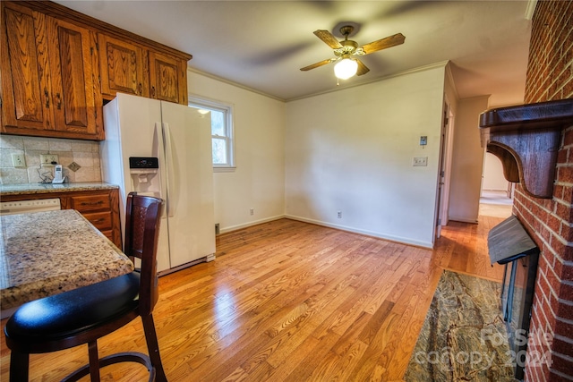 kitchen featuring backsplash, crown molding, light hardwood / wood-style flooring, and white appliances