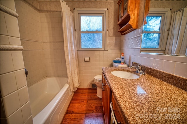 full bathroom featuring a wealth of natural light, wood-type flooring, and tile walls