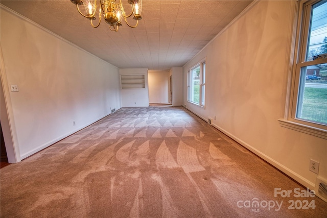 carpeted spare room with a notable chandelier and ornamental molding