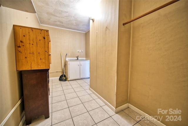 washroom featuring light tile patterned flooring, crown molding, and sink