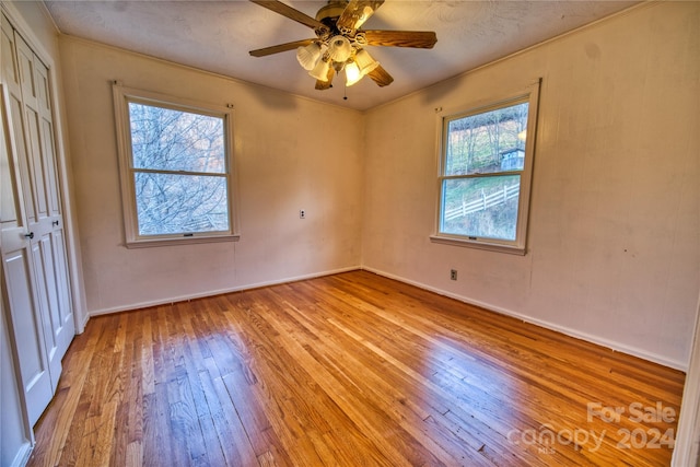 empty room featuring a textured ceiling, light wood-type flooring, ceiling fan, and crown molding