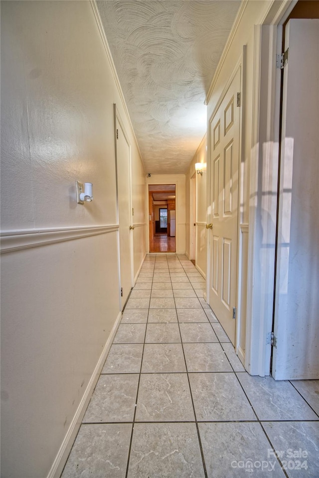 hall featuring ornamental molding and light tile patterned floors