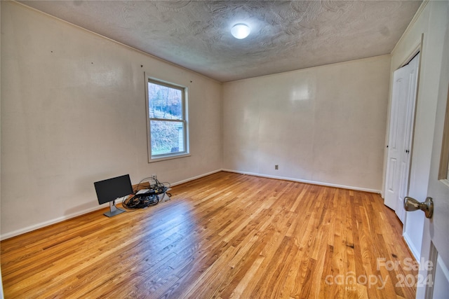 unfurnished room featuring a textured ceiling and light wood-type flooring