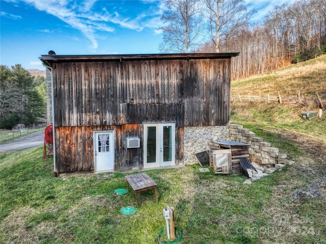 view of outbuilding featuring a yard, an AC wall unit, and french doors