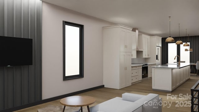 kitchen featuring sink, hanging light fixtures, electric range, a kitchen island with sink, and white cabinets