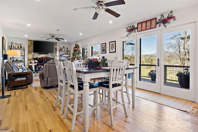 dining room featuring ceiling fan, a fireplace, and light hardwood / wood-style flooring