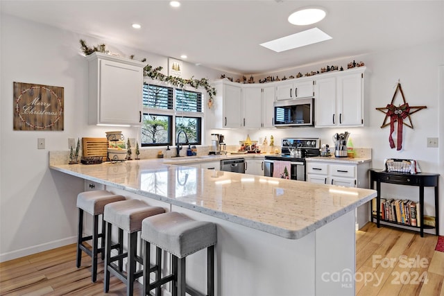 kitchen with white cabinetry, stainless steel appliances, and light wood-type flooring