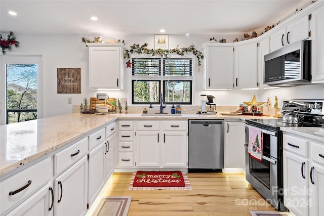 kitchen with white cabinets, light stone countertops, light wood-type flooring, and stainless steel appliances